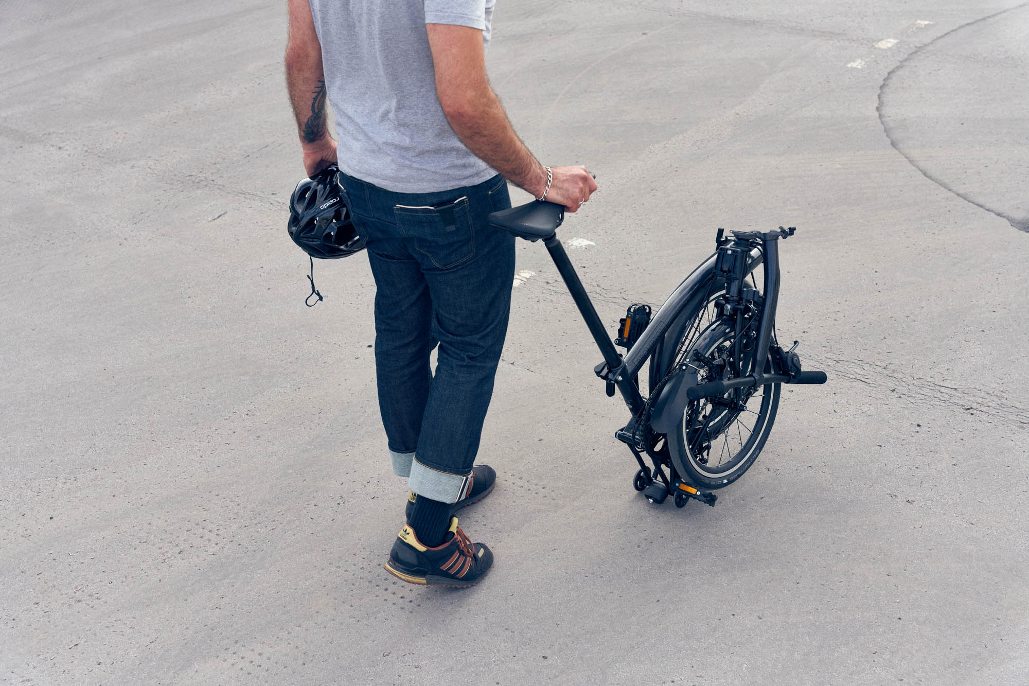 Man rolling Brompton P Line bike in folded position.