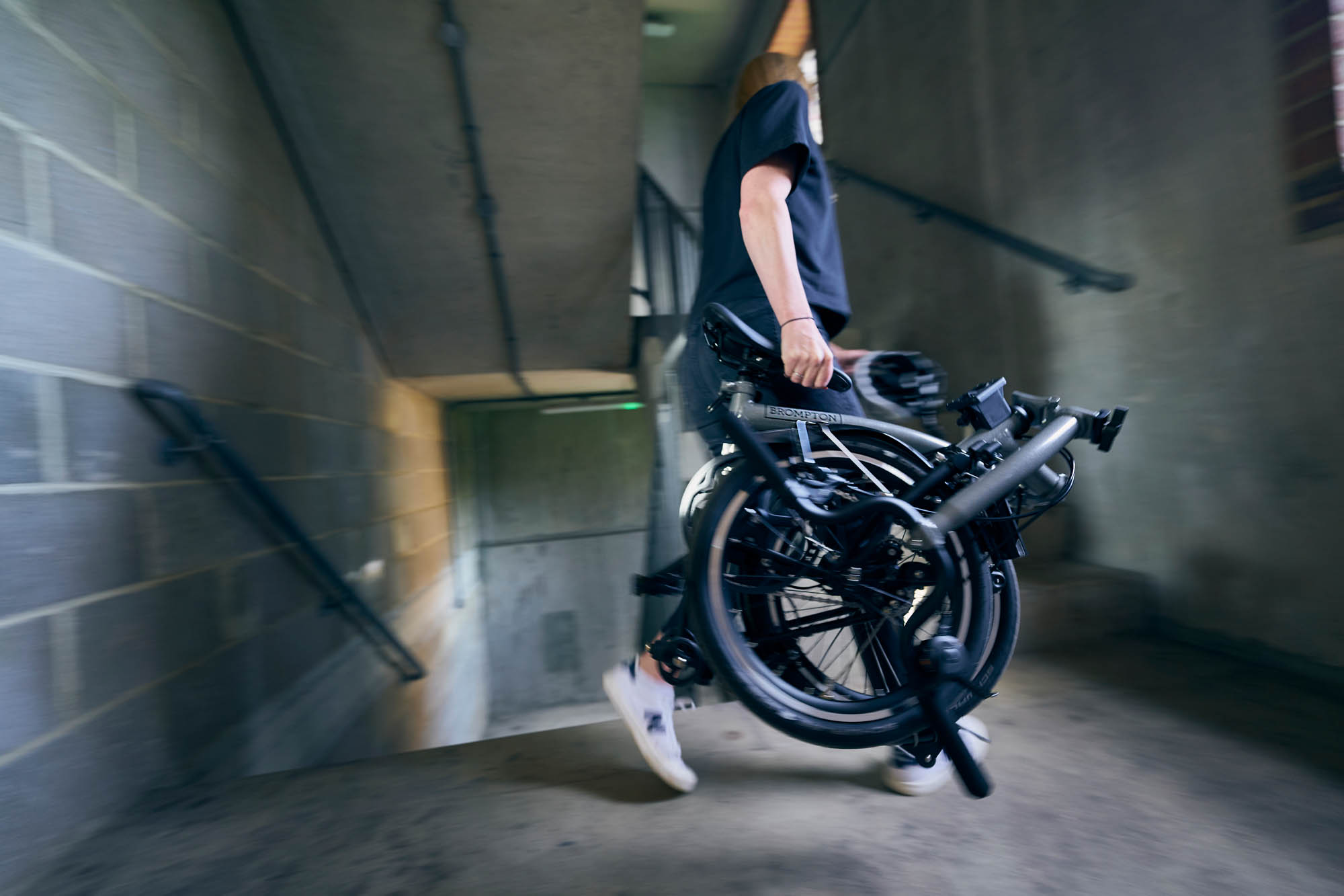 Woman carrying fully folded Brompton P Line bike.