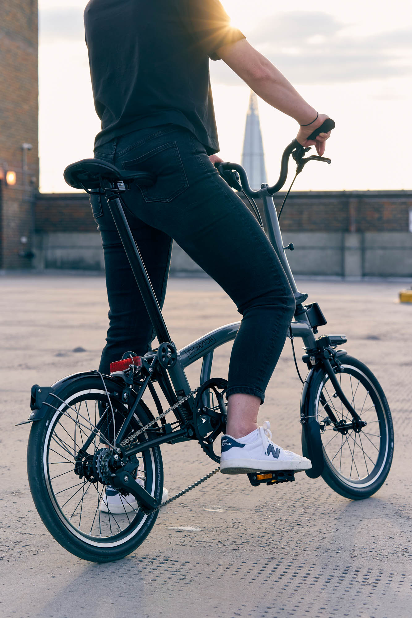 A man sitting on top of a Brompton P Line bike. Rear view.