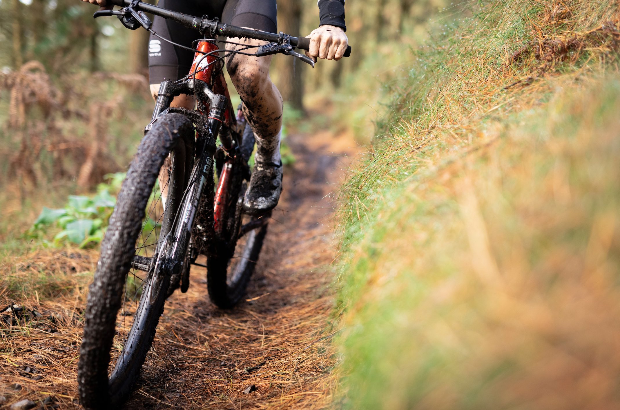 Rider on a Kenta SL in Red on single track trail. Front view.