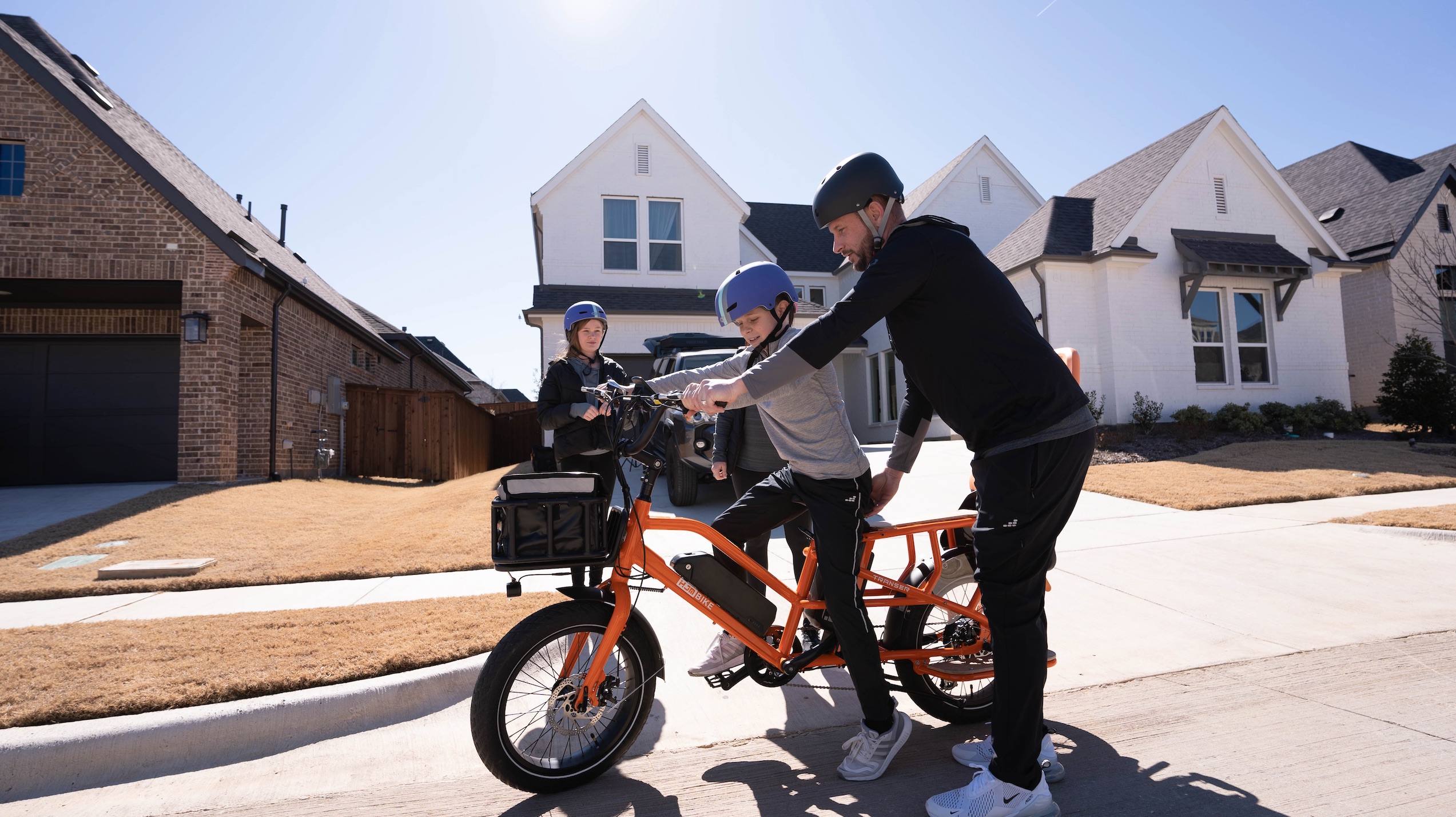Boy riding the HJM Transer Cargo e-bike in a neighborhood.
