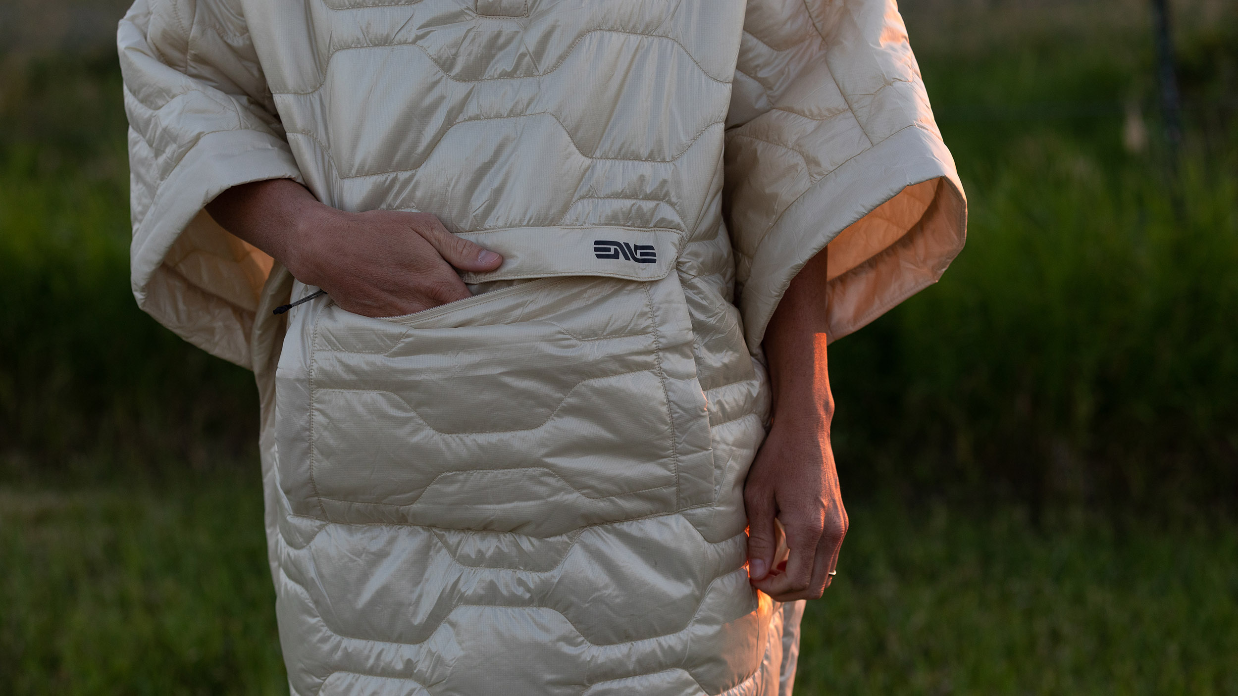 a woman with her hand in the pocket of the ENVE PrimaLoft Insulated Poncho
