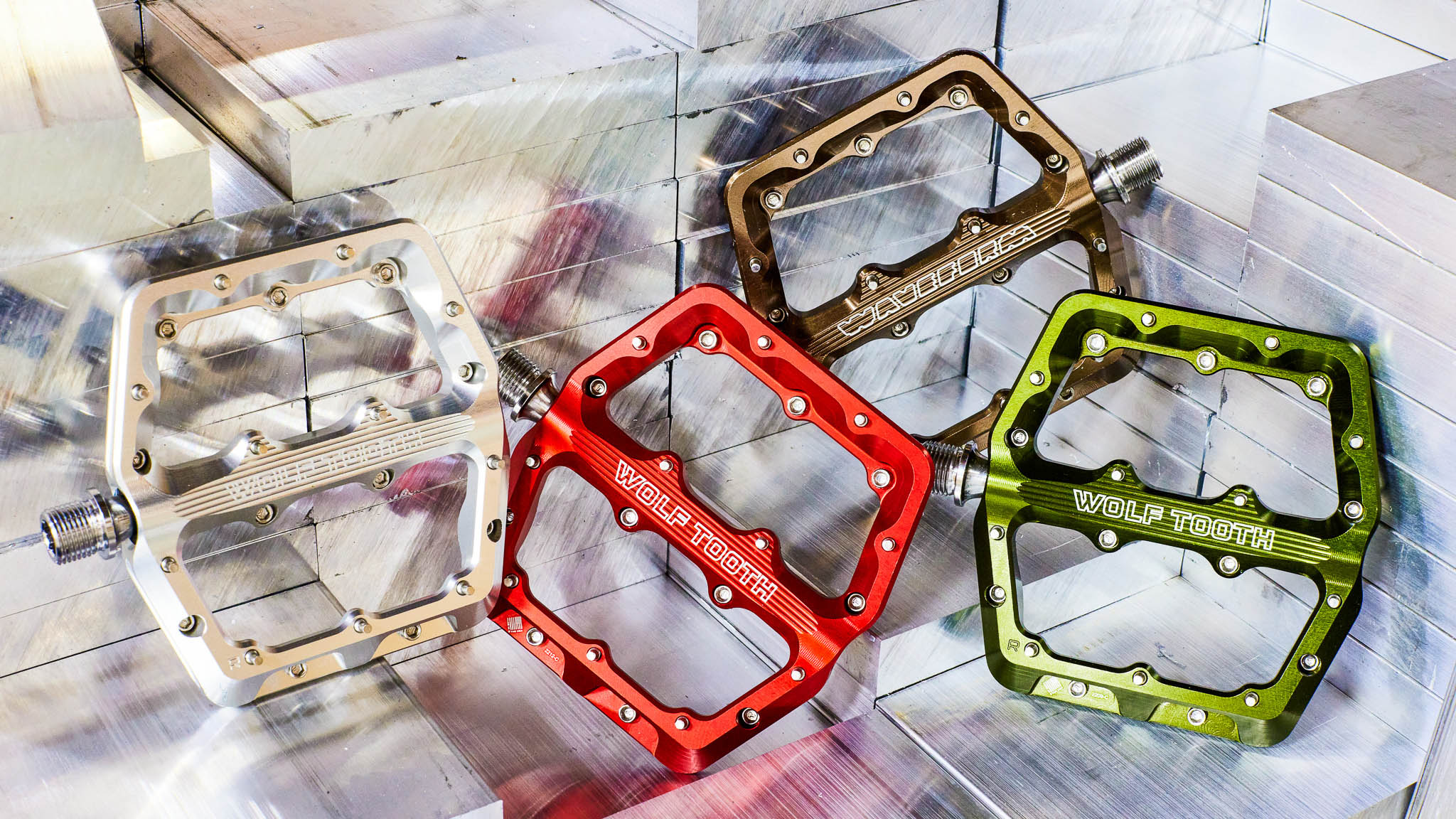 four pedals side by side. The colors from left to right are raw silver, red, espresso (brown), and olive (green).