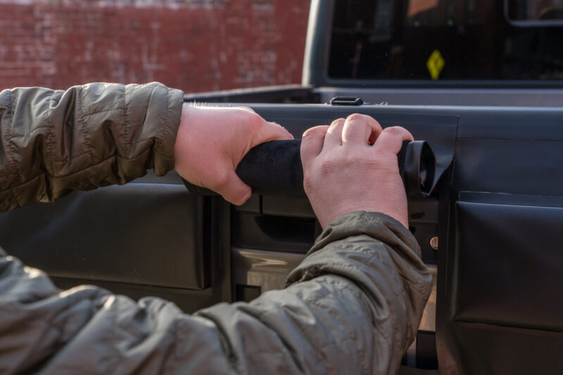 man rolling up a panel in a tailgate pad to expose the tailgate latch