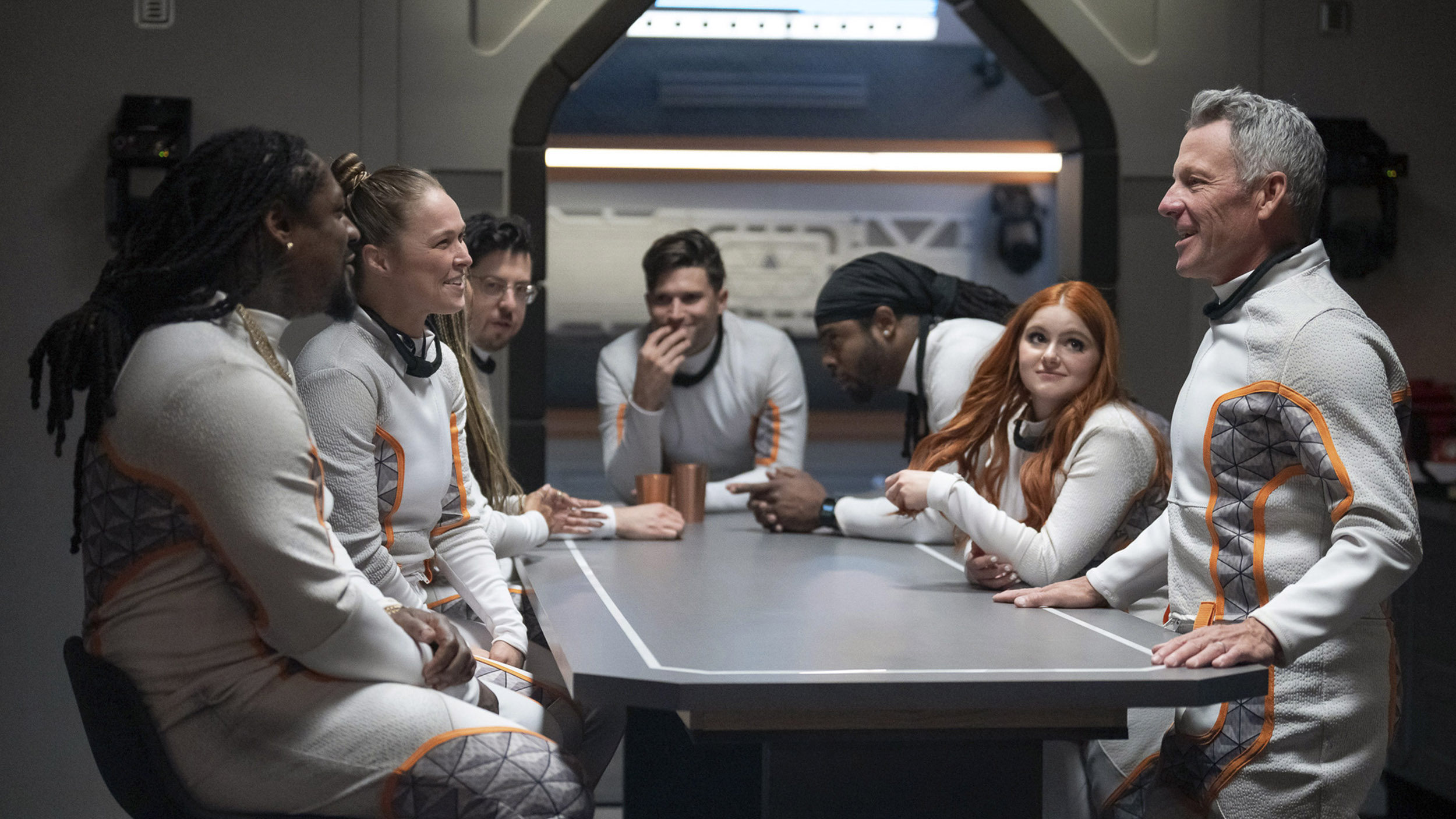 a group of people stand around a table