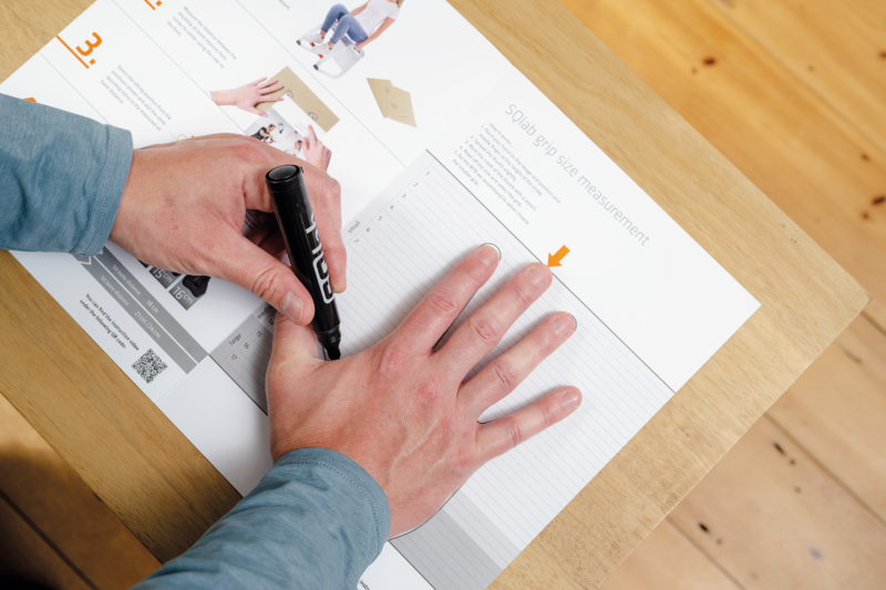 A man measuring his hand with the SQlab home measurement kit.