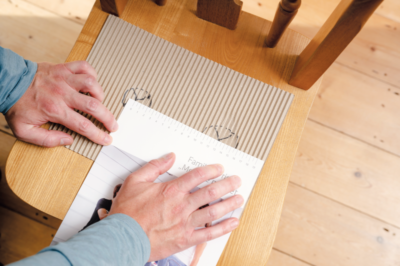 A man measuring his sit bone width on a piece of cardboard provided in the SQlab home measurement kit.