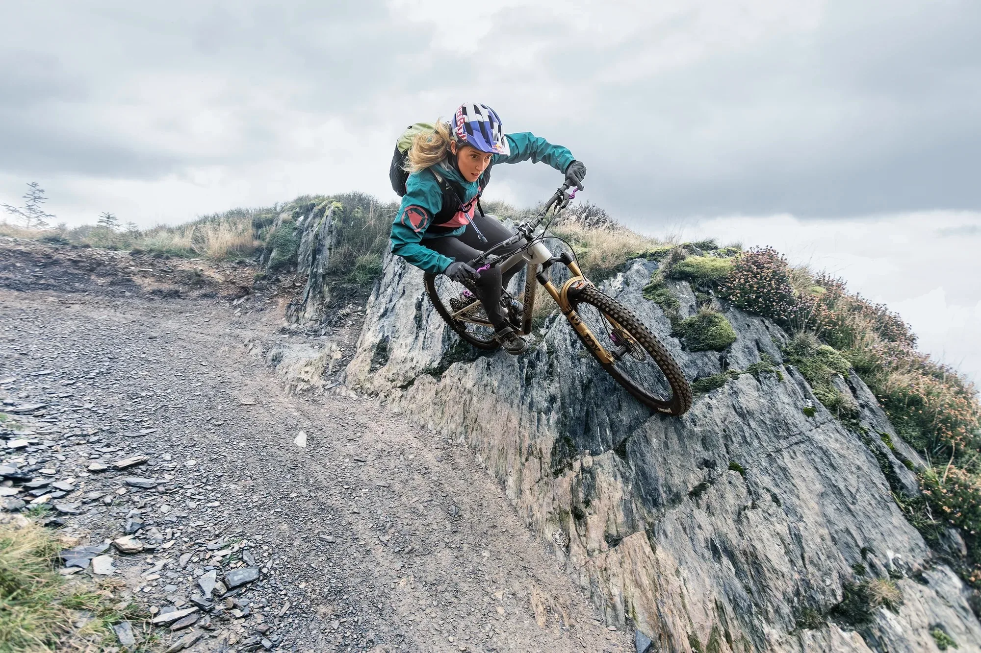 A female rider riding down some aggressive terrain while wearing the Hiline pack.