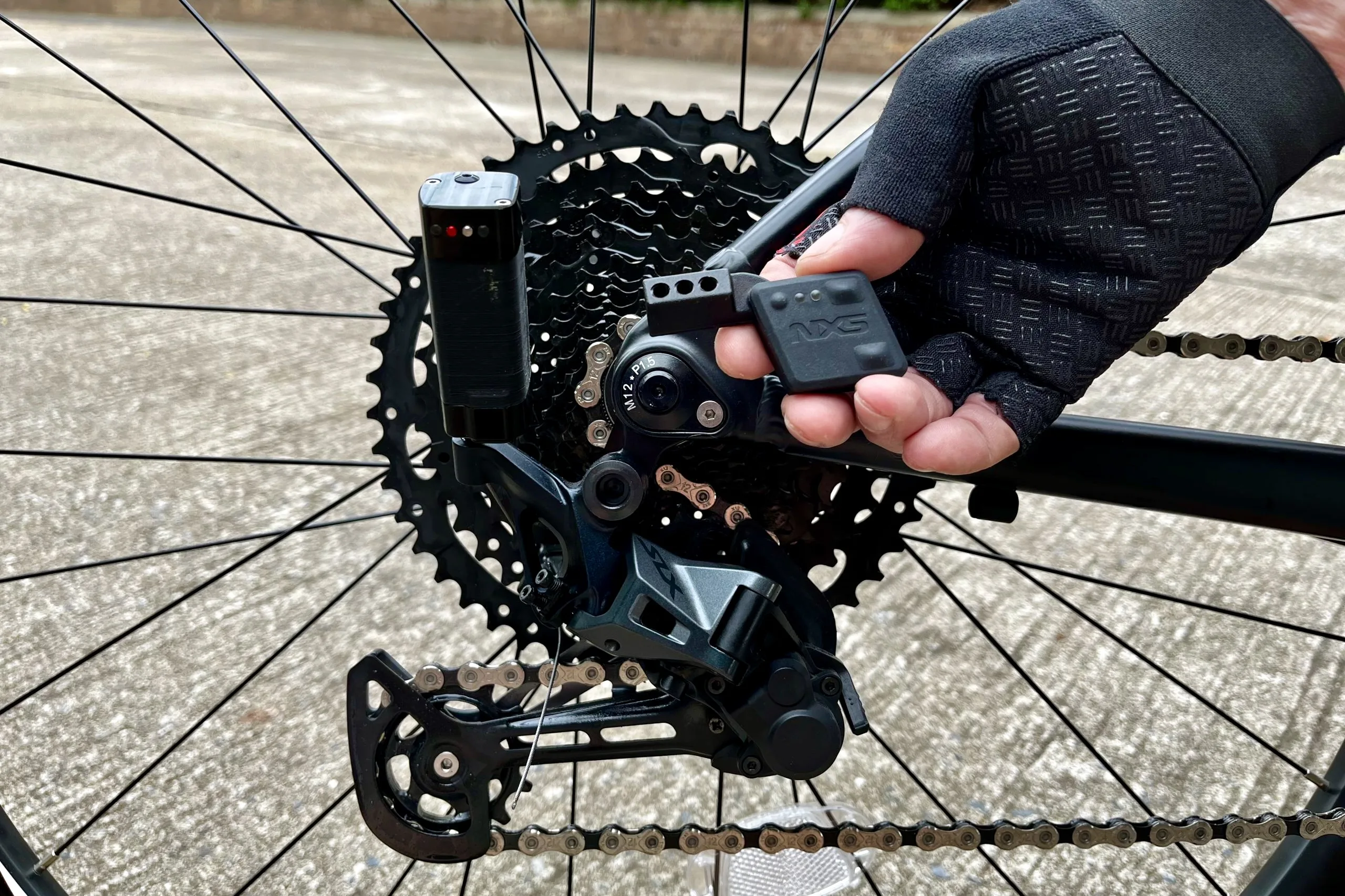 The NXS Wireless shifter attached to a Shimano derailleur with someone holding the wireless remote