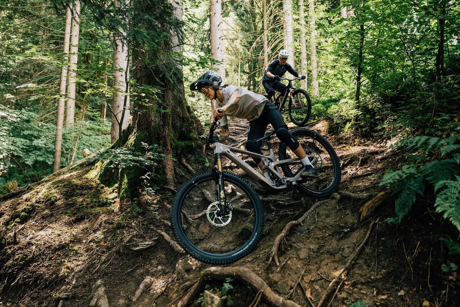 Two rider on the new Propain Hugene bikes navigating a rooty trail