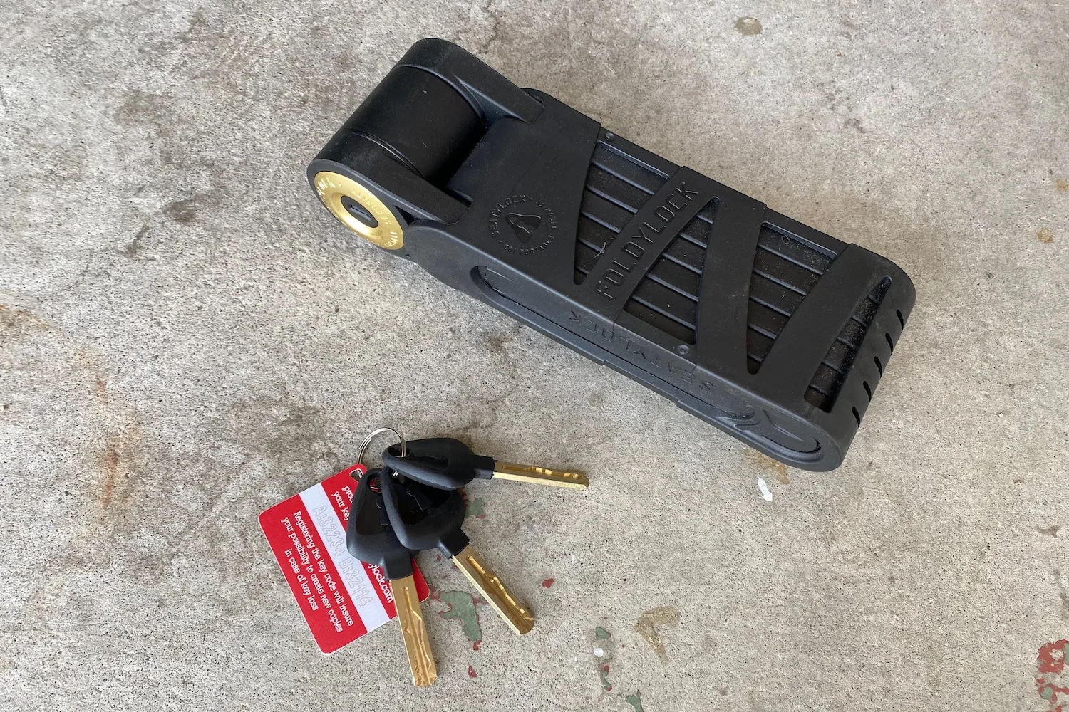 The Foldylock Forever in its mounting bracket with the 3 included keys next to it.