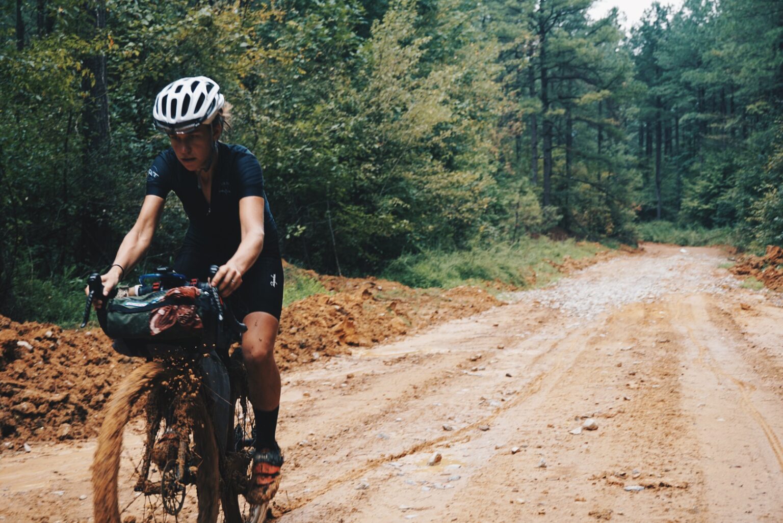 Swallow riding along a wooded dirt road on her 2015 TAT adventure