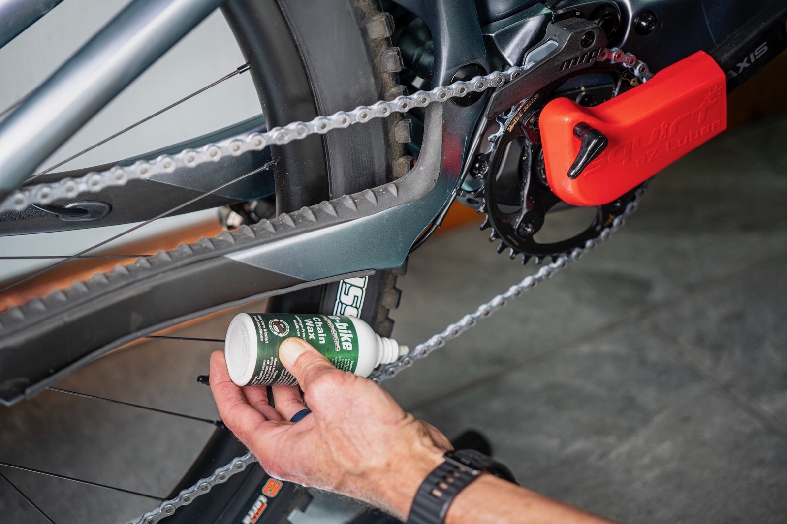 a person lubing and e-bike chain while using the Squirt EZ-Luber.
