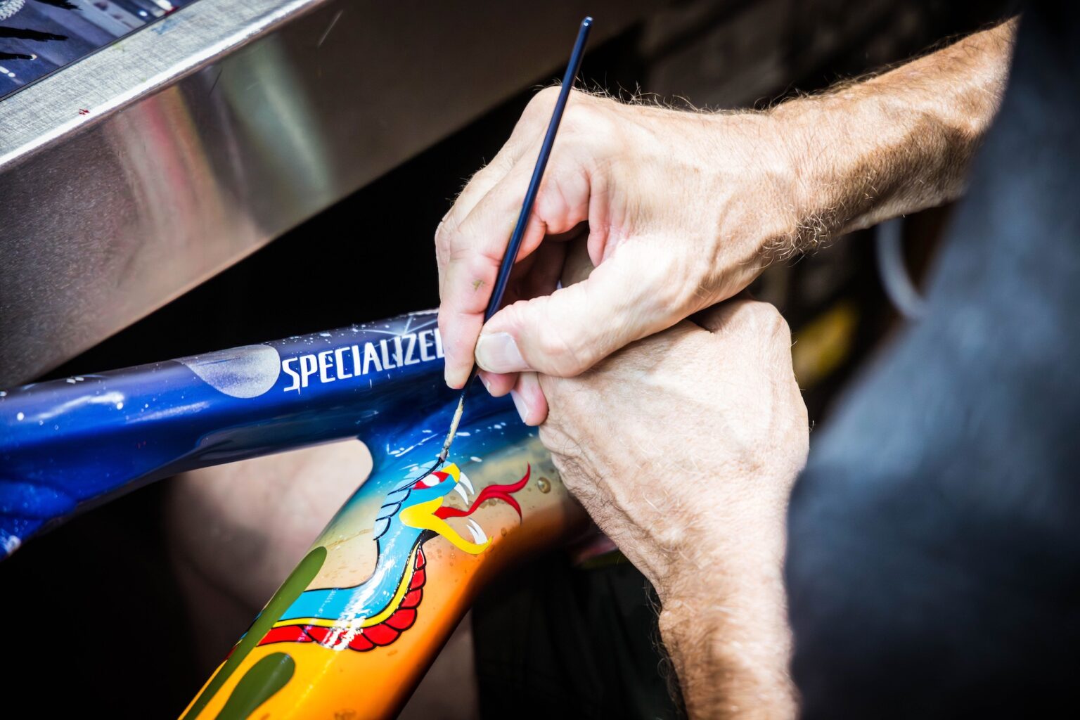 A person painting a bike frame by hand.