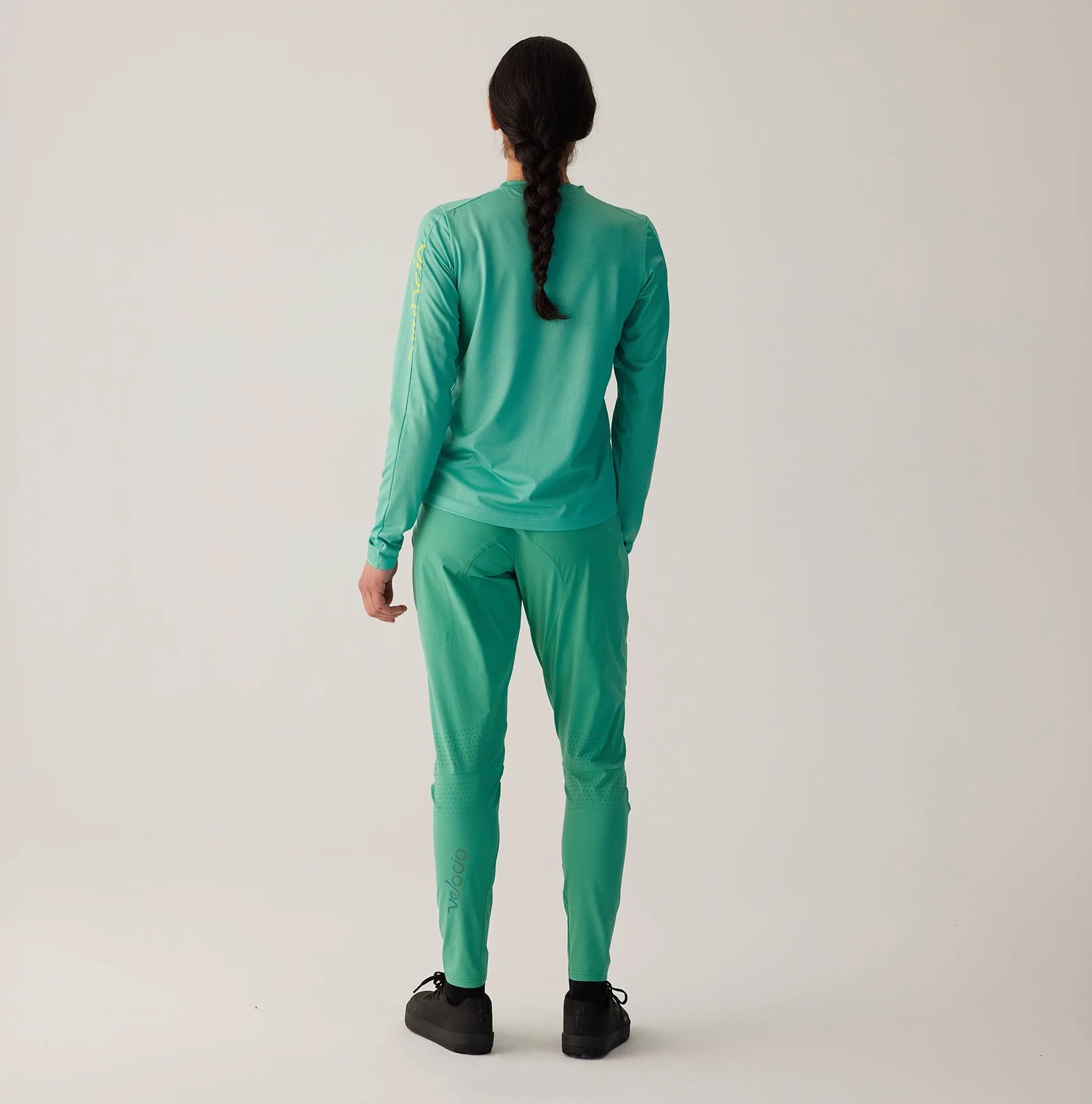 Studio image of a woman wearing the Velocio Ultralight Trail Pants from the rear.