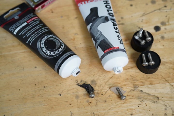 A tube of Silca Hold Fast carbon paste next to a tube of Silca Synergetic Race Grease on a work bench.