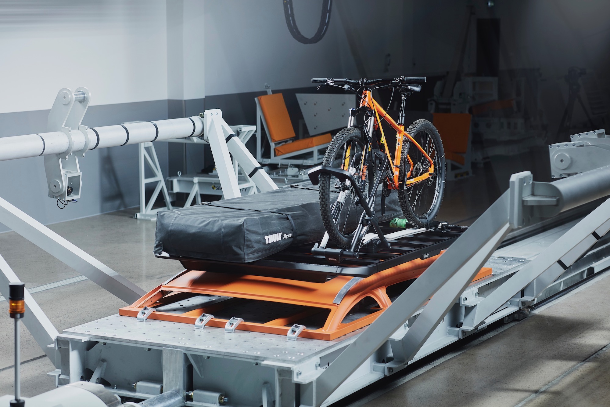 a vehicle roof with a luggage rack, bike rack, and rooftop tent attached for crash testing.