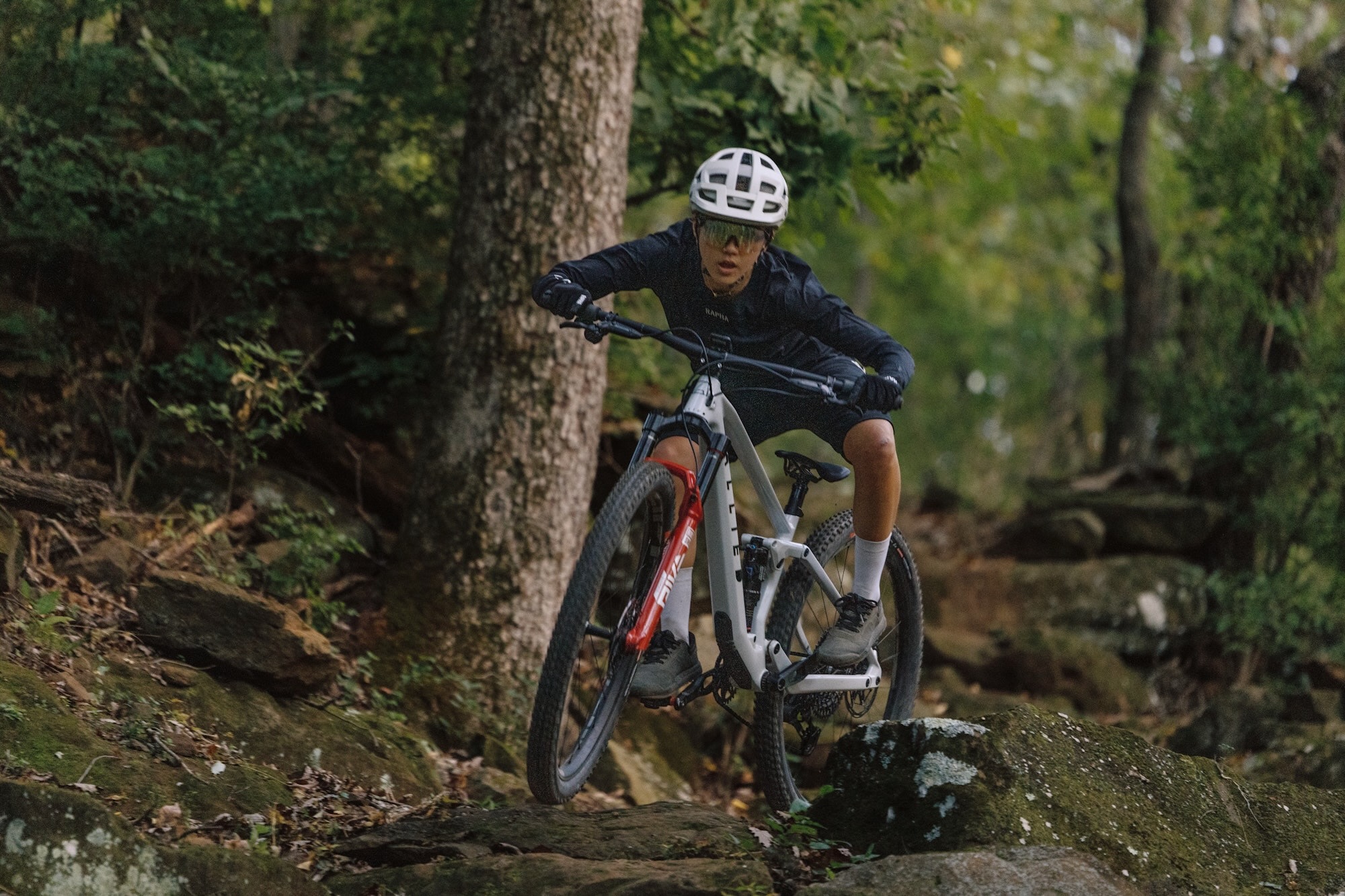 a female rider on the FITZ trail bike in the forest on a rocky trail