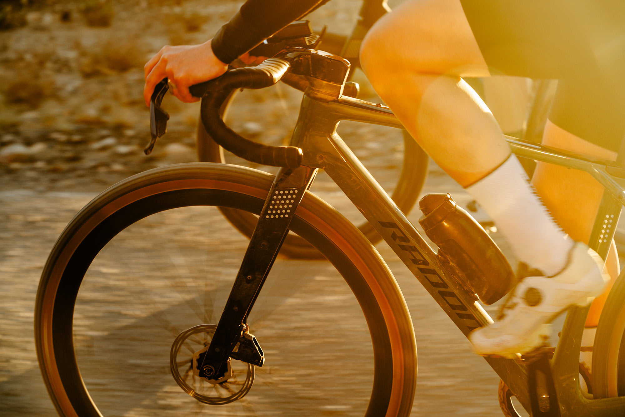 closeup of radon regard carbon gravel bike being ridden on dirt road.