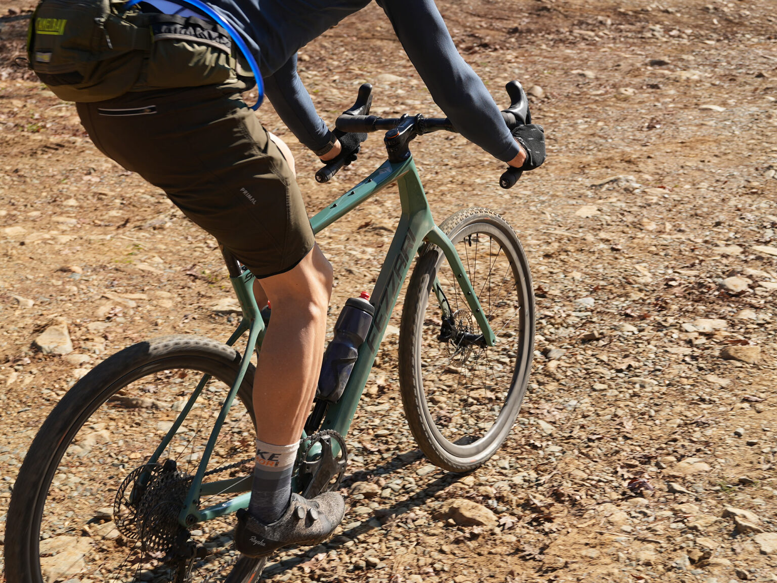 cyclist riding bike with fulcrum rapid red carbon gravel wheels.