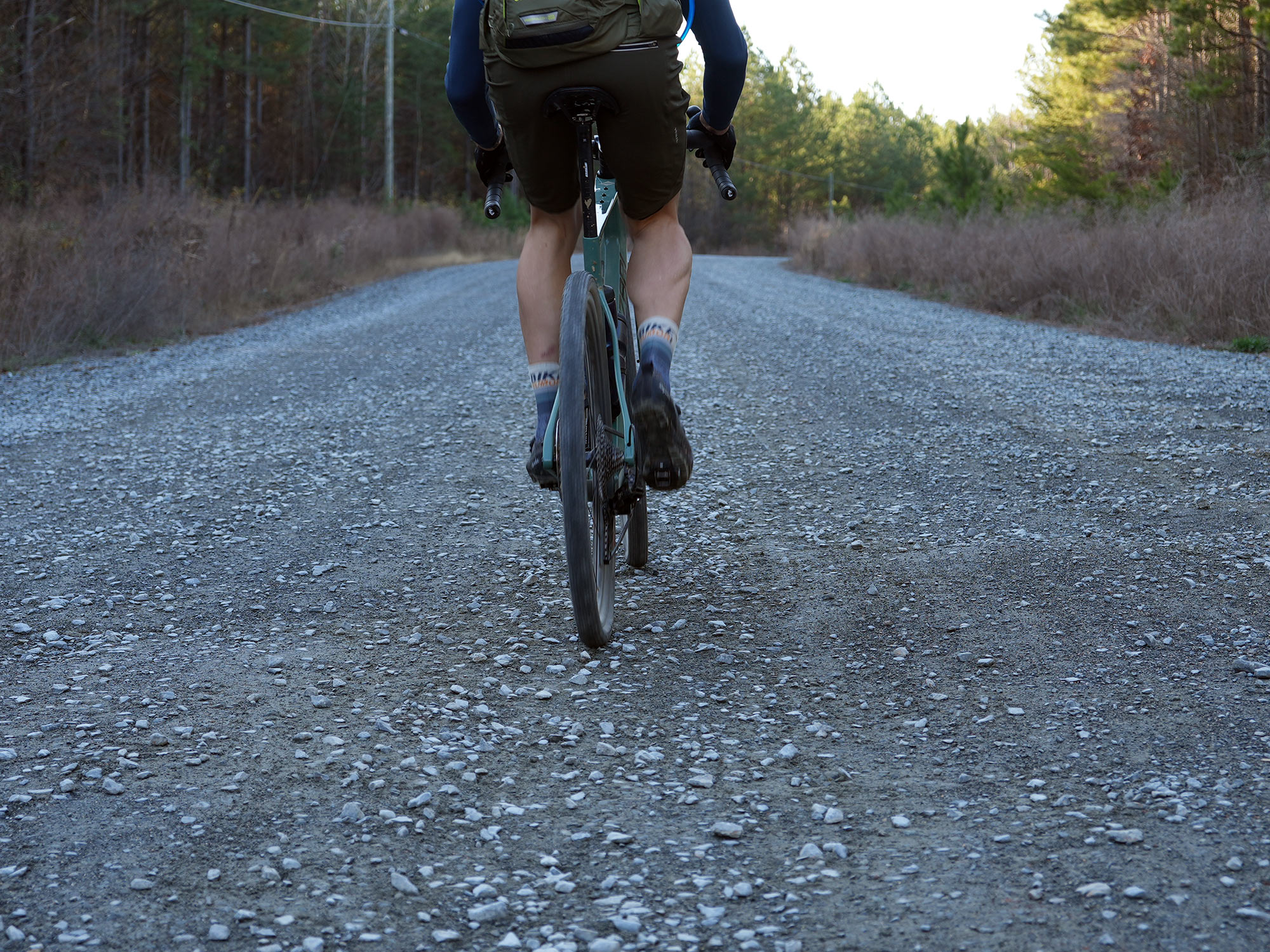 cyclist riding bike with fulcrum rapid red carbon gravel wheels.