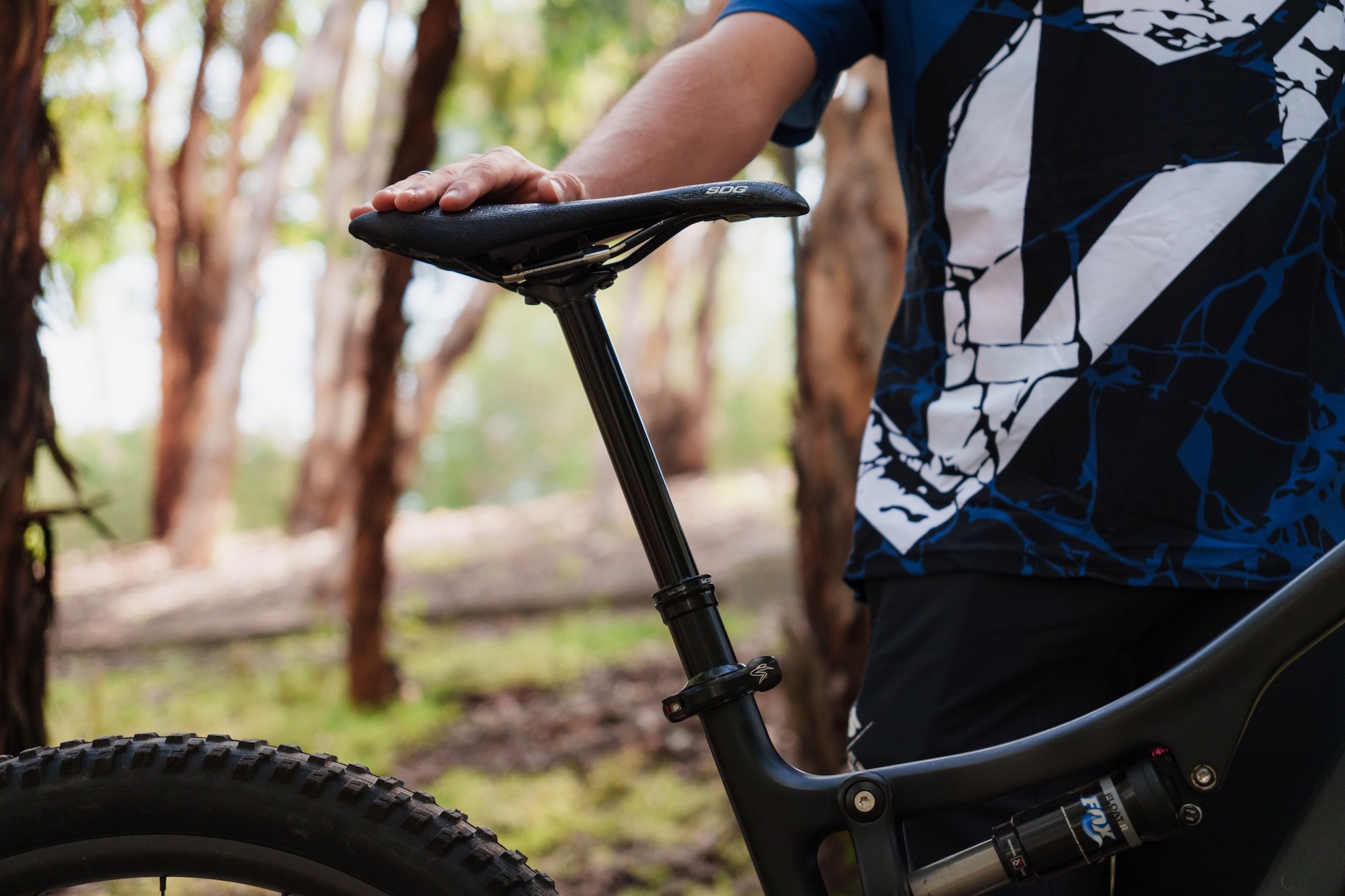 a person standing next to a bike with the KS Rage-i dropper with their hand on the saddle.