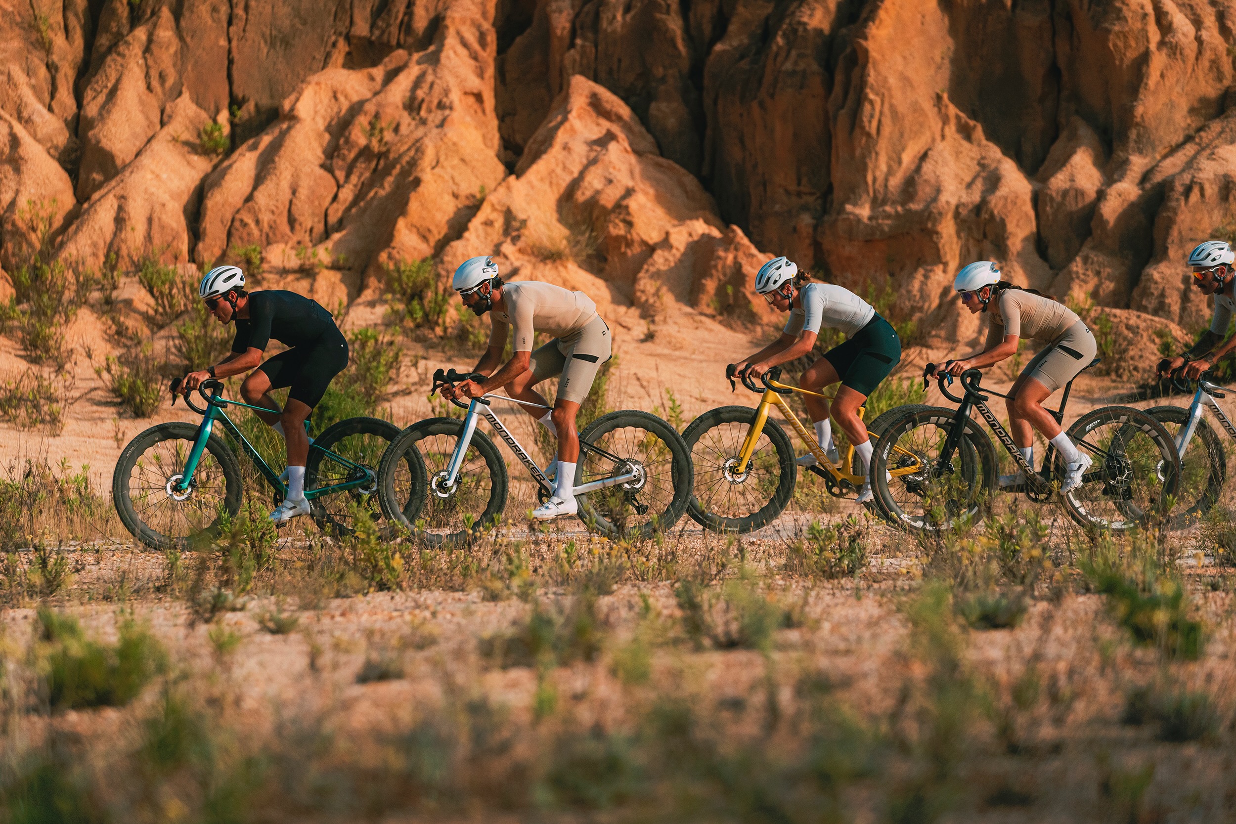 a group of riders on the Mondraker Arid gravel bike riding through a desert landscape.