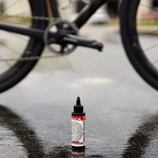 image of the silca Super Secret 2.0 bottle sitting in a paved road in front of a bike