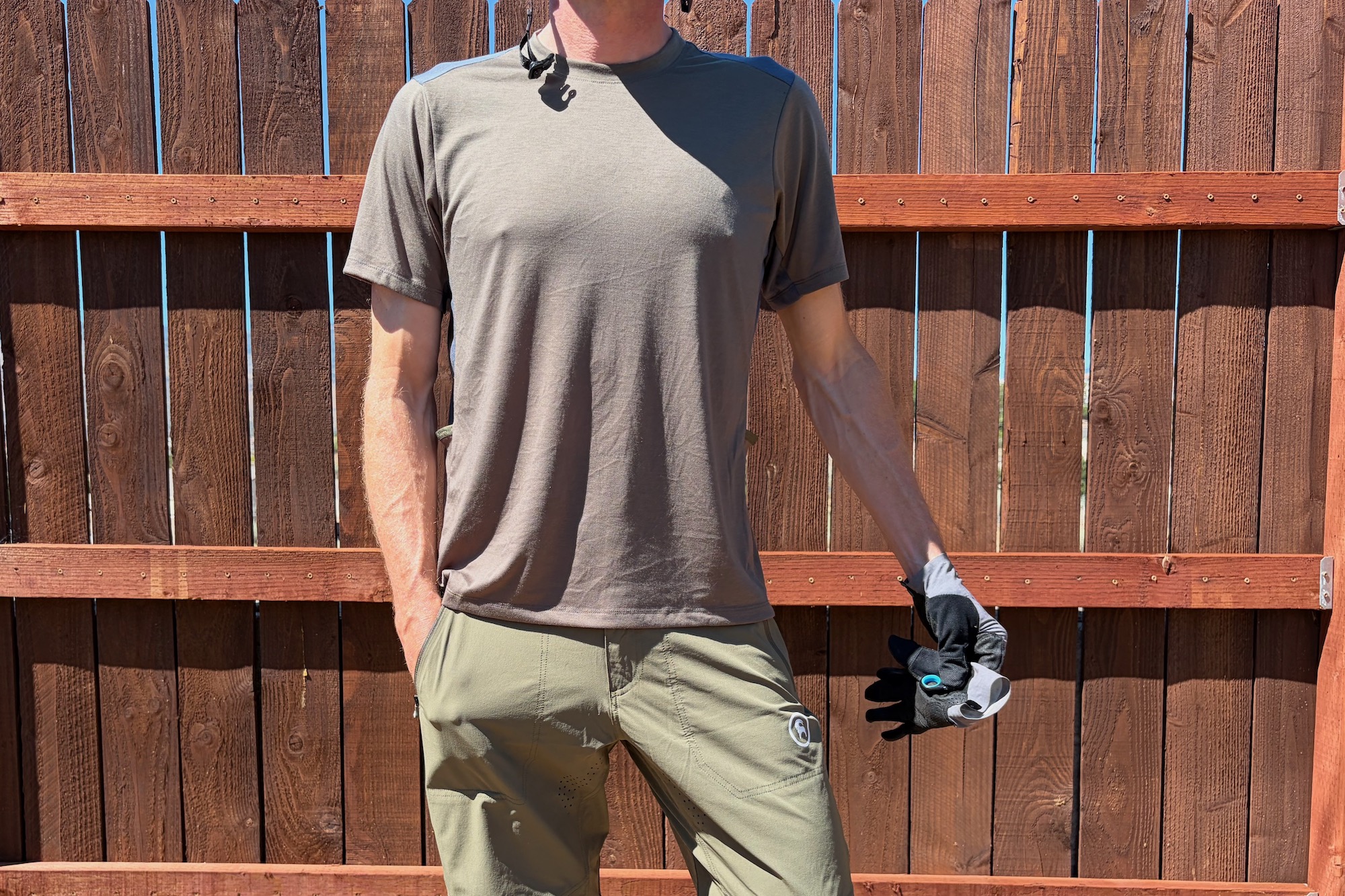 wearing the slickrock tech T standing by a fence, viewed from the front
