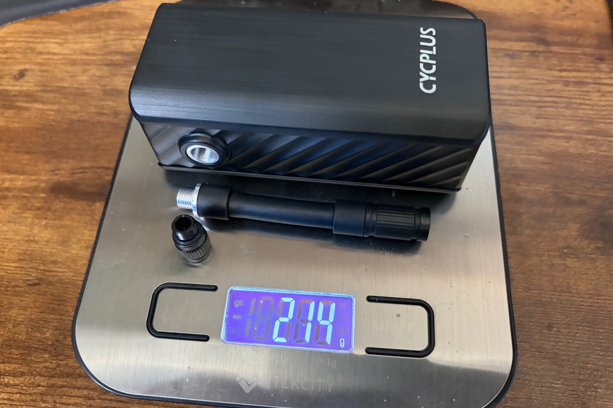the Cycplus A3 Mini on a digital scale with the extension hose and a weight of 214 grams